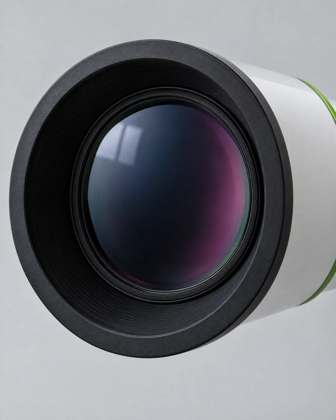 The large coated front lens of a white Sky-Watcher refractor inside its black front ring, with a thin lime-green ring on the tube behind