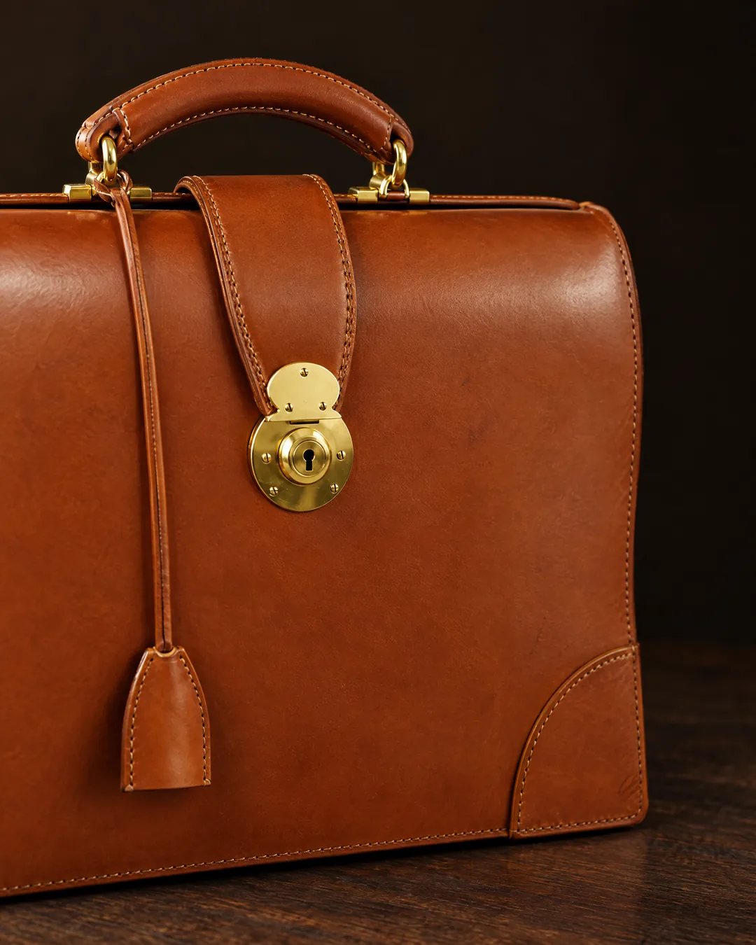 A tan bridle-leather A-frame briefcase with a brass lock and handle