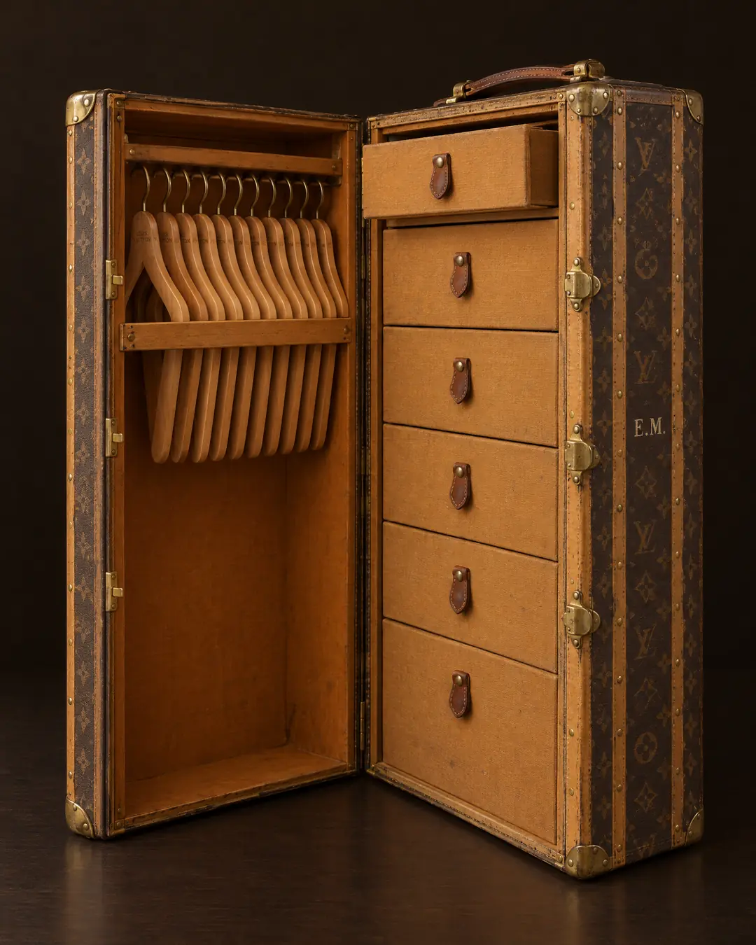 An open Louis Vuitton monogram wardrobe trunk, wooden hangers on one side and six drawers on the other