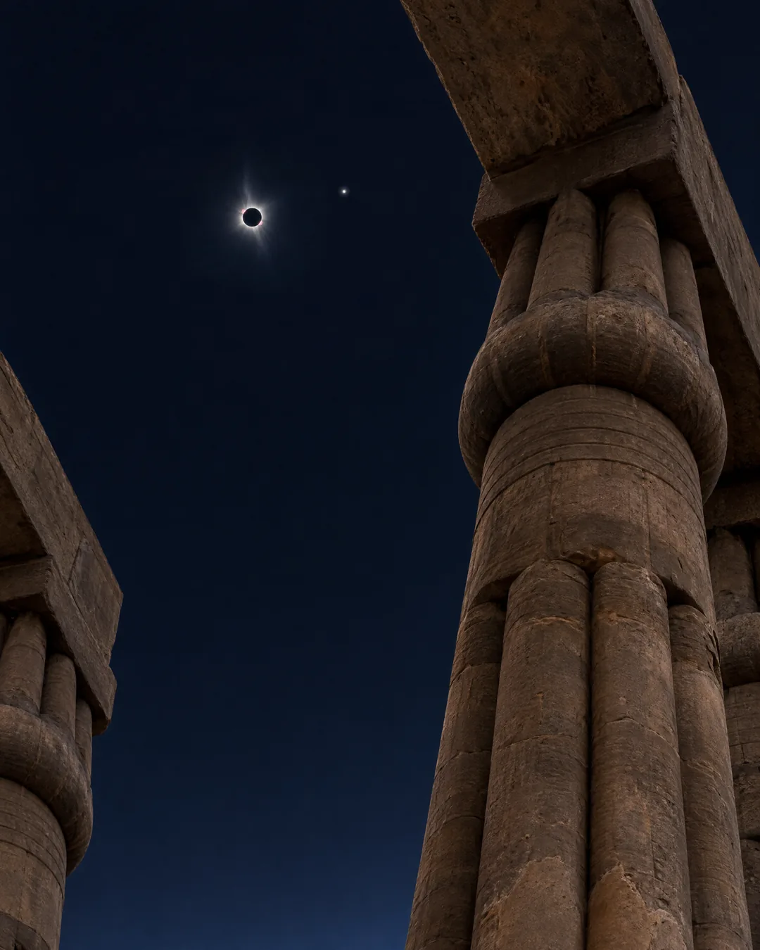 A total solar eclipse high above a papyrus bundle column in Luxor Temple