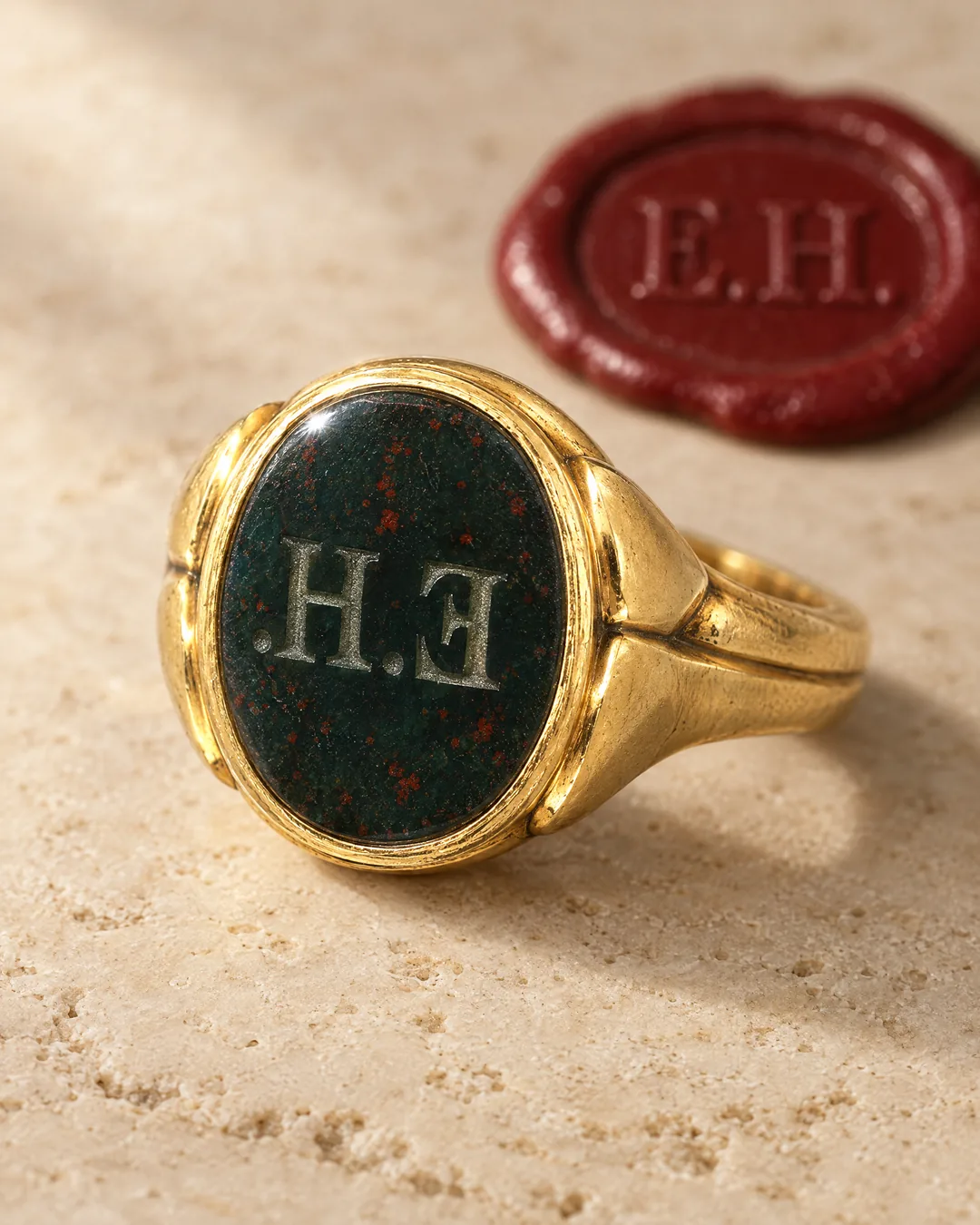 A gold bloodstone signet ring with the initials E.H. cut in reverse, beside a red wax impression